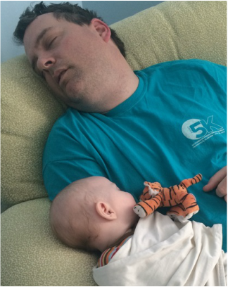 Photo of a tired dad sleeping with his son after rocking him.
