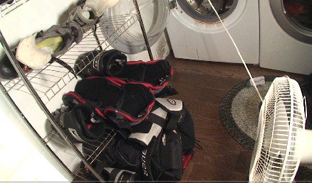 Picture of hockey gear with a fan in the laundry room