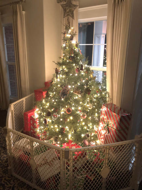 This Authentic Home Christmas tree surrounded by Christmas presents and a baby gate to keep the dogs away.